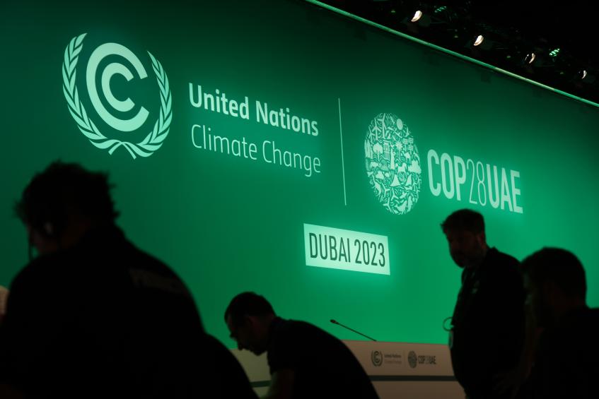 Green screen with the words UN Climate Change written on it, with silouetted figures in front