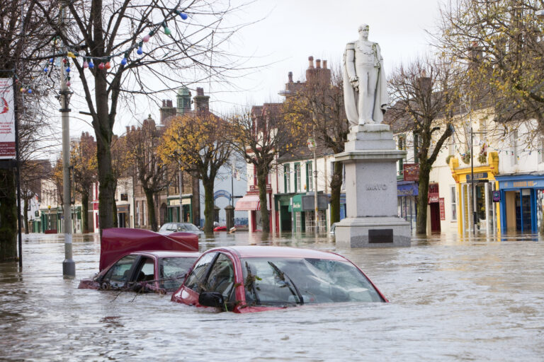 A flooded street showing cars barely visible under the flood water.